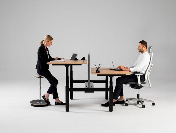 Bureau réglable partagé avec deux personnes, l\'une debout, l\'autre assise