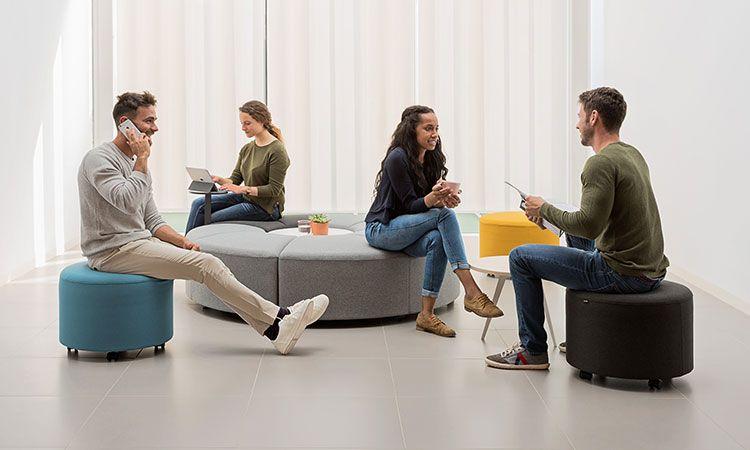 Personnes assises sur des poufs Comino dans un espace lounge lumineux