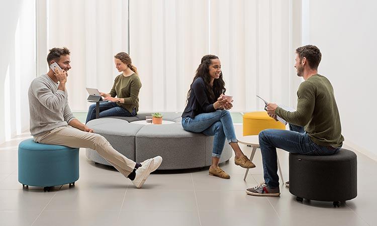 Personnes discutant assises sur des poufs dans un espace de coworking