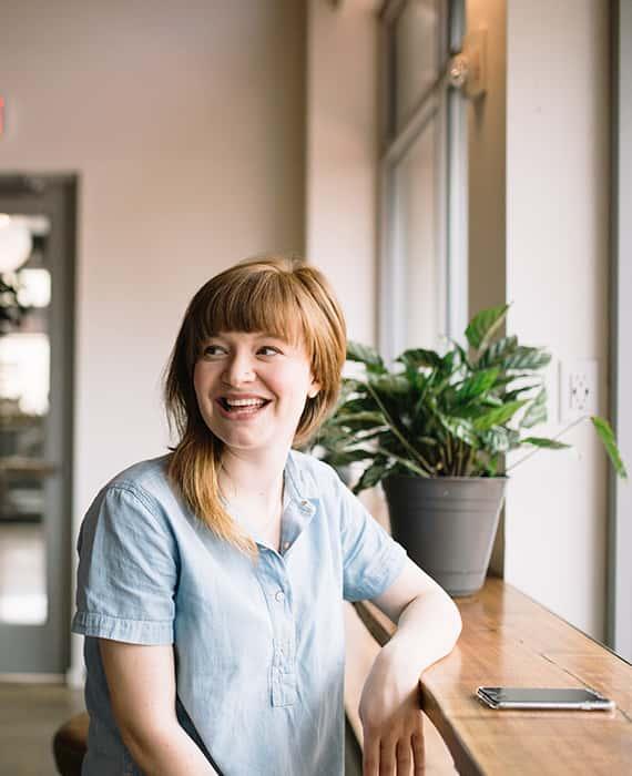 Femme souriante assise à une table près d\'une fenêtre