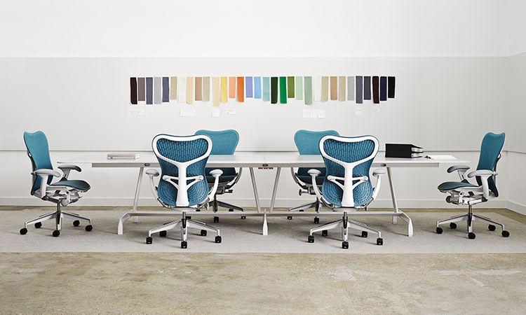 Fauteuils ergonomiques Mirra 2 bleus autour d\'une table, nuancier mural