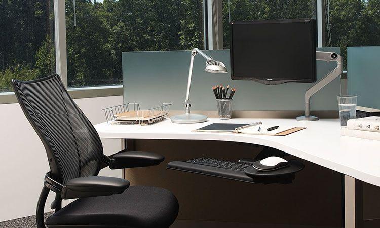 Poste de travail avec écran sur bras support et fauteuil ergonomique, baies vitrées