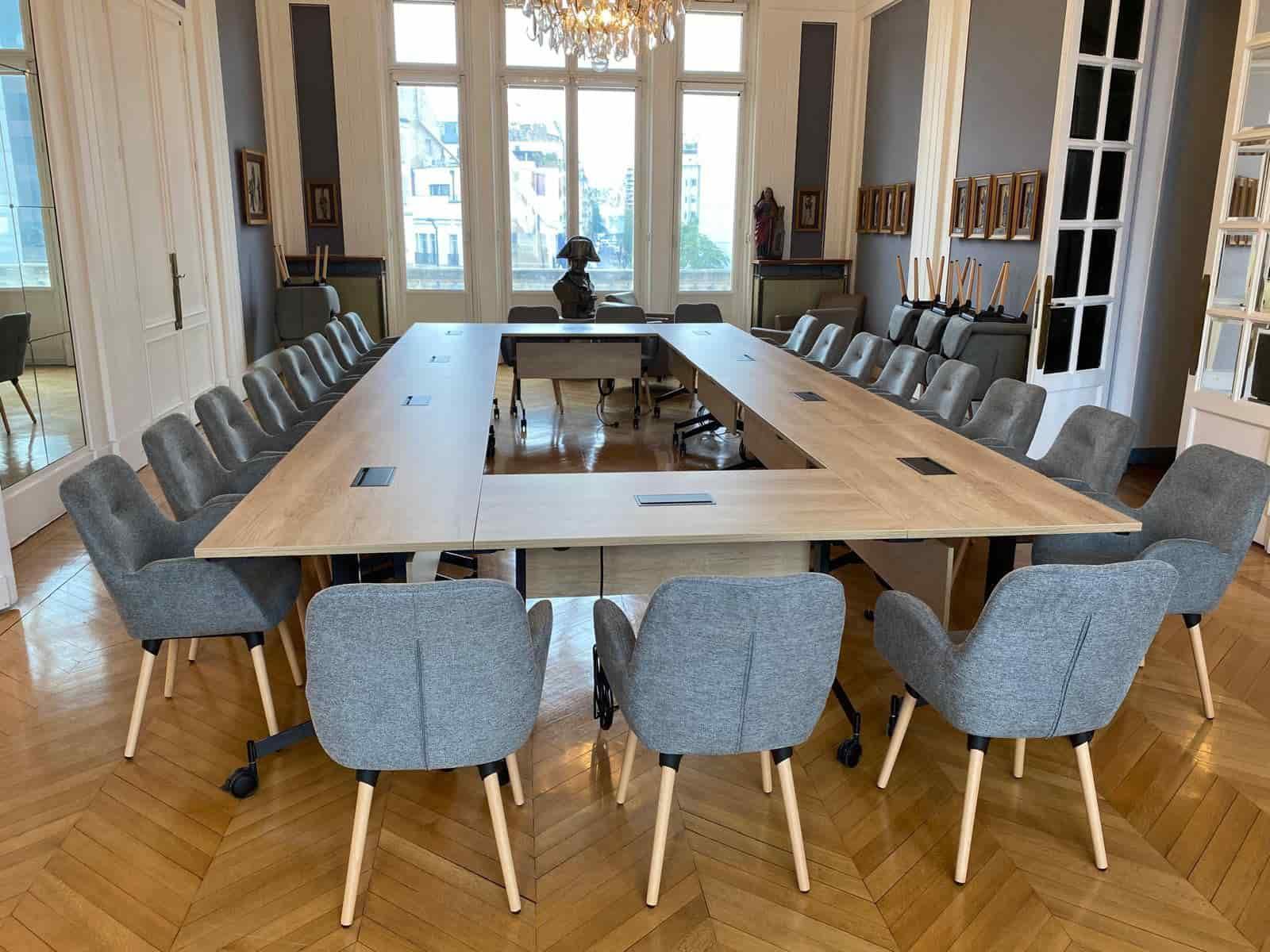 Salle de réunion élégante avec table en bois, fauteuils gris et lustre