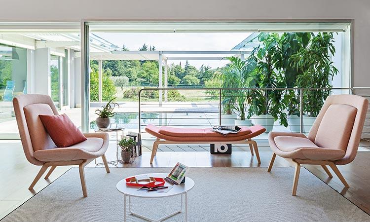 Salon lounge avec fauteuils Athos en cuir et table basse devant une véranda