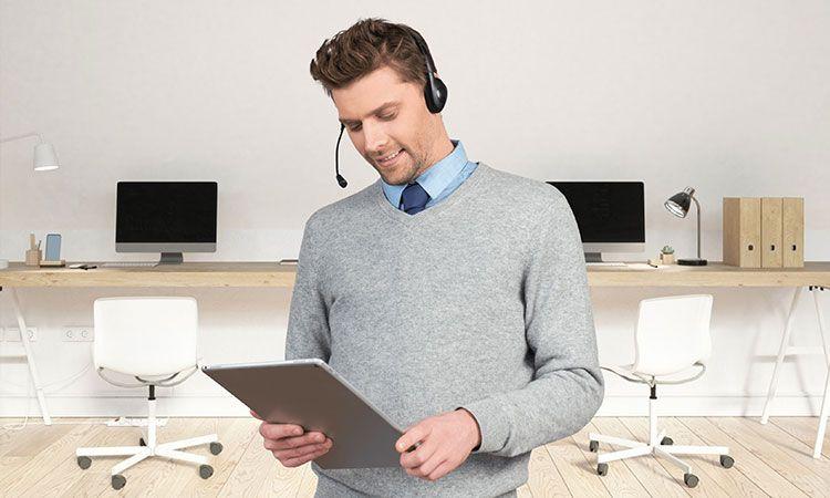 Conseiller avec casque téléphonique tenant une tablette dans un bureau