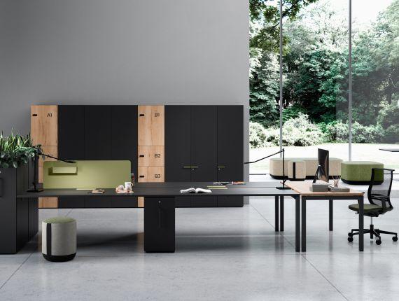 Open space avec bureaux noirs et bois, fauteuils et plantes devant une baie vitrée