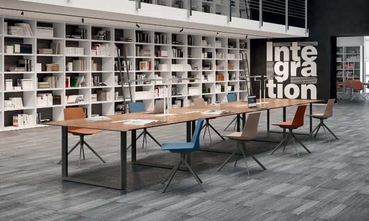 Table de réunion en bois avec chaises colorées devant une grande bibliothèque